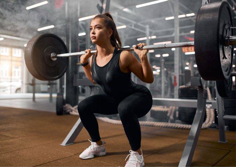 Image of a woman performing one of rhinofit's leg workouts with barbell