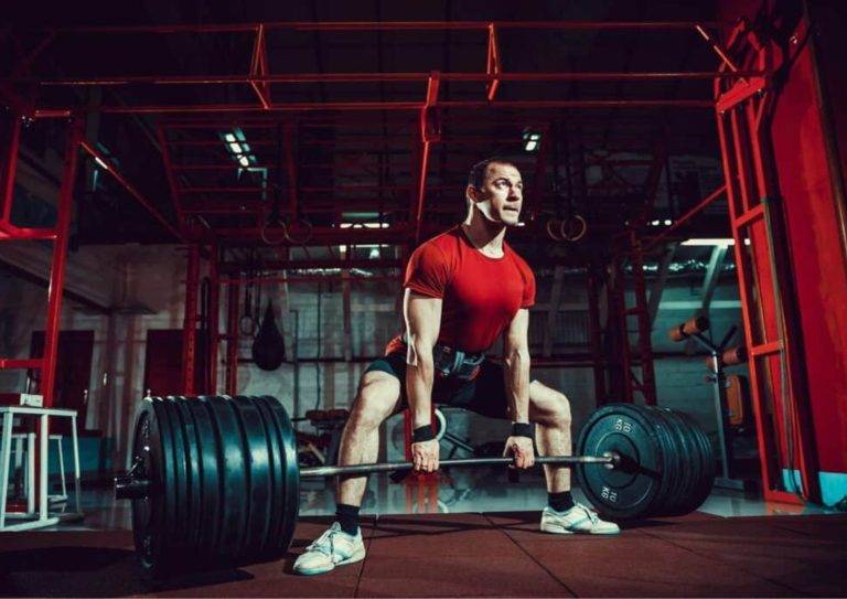 Image of a man performing one of our sumo deadlift leg workouts with barbell