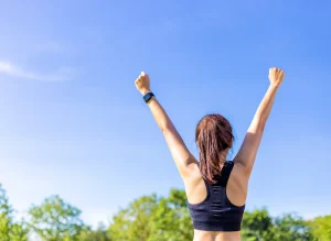 Image of a woman exercising outside with her arms raised up