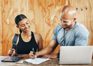 Image of a gym owner and gym member filling out paperwork at the gym front desk