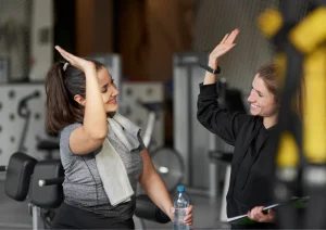 Image of a gym owner and gym member high-fiving at the gym