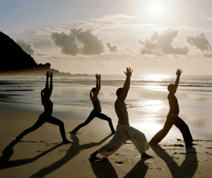 Image of yoga studio members at the beach practicing exercises